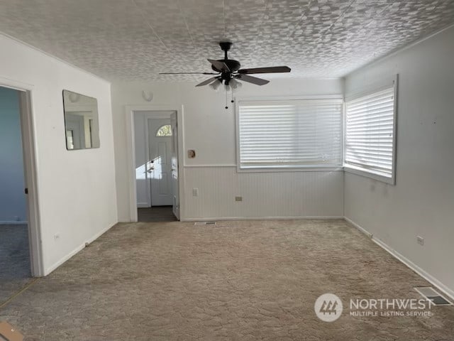 205 Monroe St, Ryderwood, WA 98581 - unfurnished living room featuring a ceiling fan, a wainscoted wall, and carpet