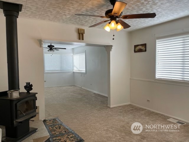 205 Monroe St, Ryderwood, WA 98581 - unfurnished living room featuring a ceiling fan, visible vents, carpet, and a wood stove