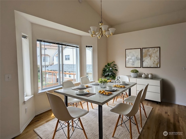 dining room featuring high vaulted ceiling, wood-type flooring, and a chandelier