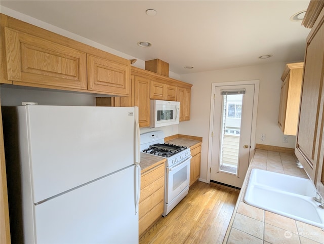 kitchen with light wood-type flooring, sink, and white appliances