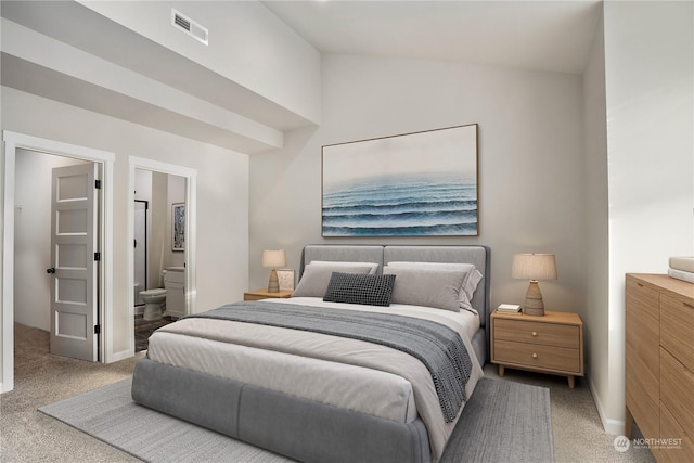 carpeted bedroom featuring vaulted ceiling and ensuite bath