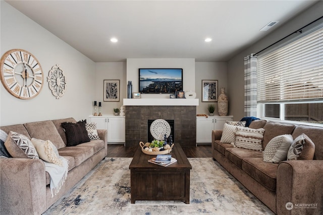 living room with a tile fireplace and light hardwood / wood-style flooring