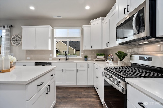 kitchen with tasteful backsplash, appliances with stainless steel finishes, dark hardwood / wood-style flooring, white cabinets, and sink