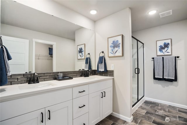 bathroom featuring a shower with door, vanity, and decorative backsplash