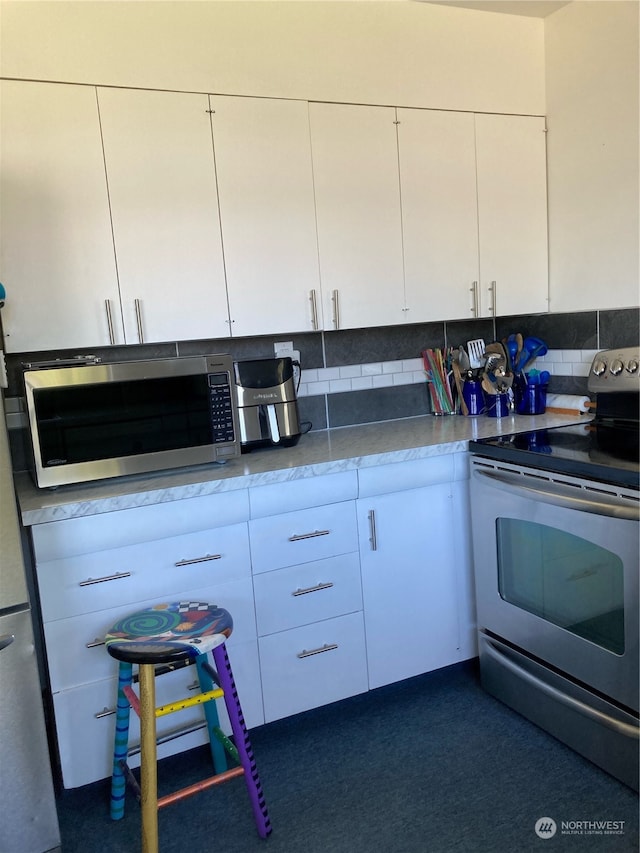 kitchen with white cabinets, appliances with stainless steel finishes, and decorative backsplash