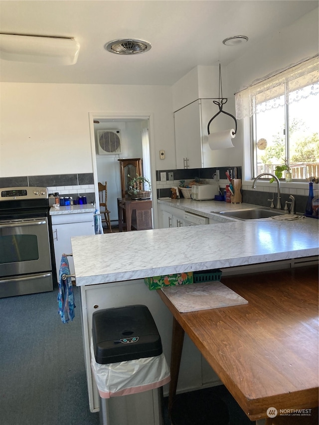 kitchen with white cabinets, electric stove, kitchen peninsula, and sink