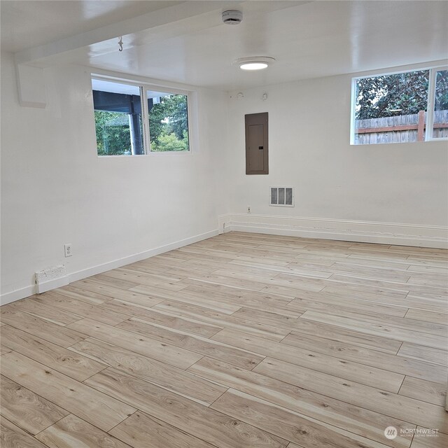 empty room with electric panel and light hardwood / wood-style flooring