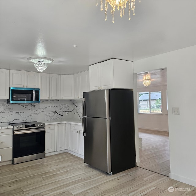 kitchen with appliances with stainless steel finishes, white cabinetry, light hardwood / wood-style flooring, and a chandelier