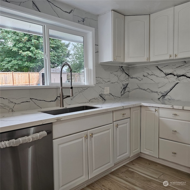 kitchen featuring dishwasher, light stone counters, light hardwood / wood-style flooring, and white cabinets