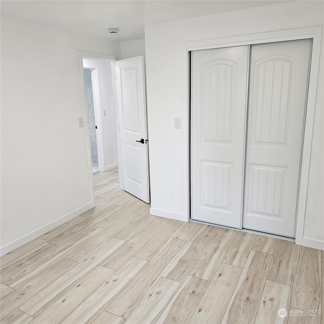 unfurnished bedroom featuring light wood-type flooring and a closet