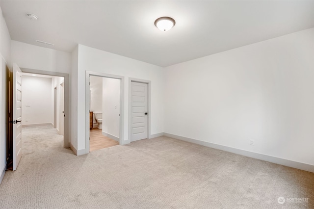 unfurnished bedroom featuring a closet and light colored carpet