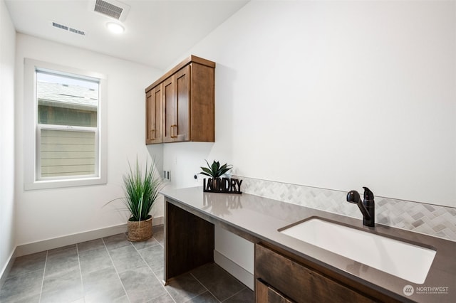 laundry room featuring sink and light tile patterned floors