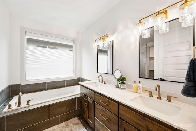 bathroom with a wealth of natural light, tile patterned floors, tiled tub, and vanity