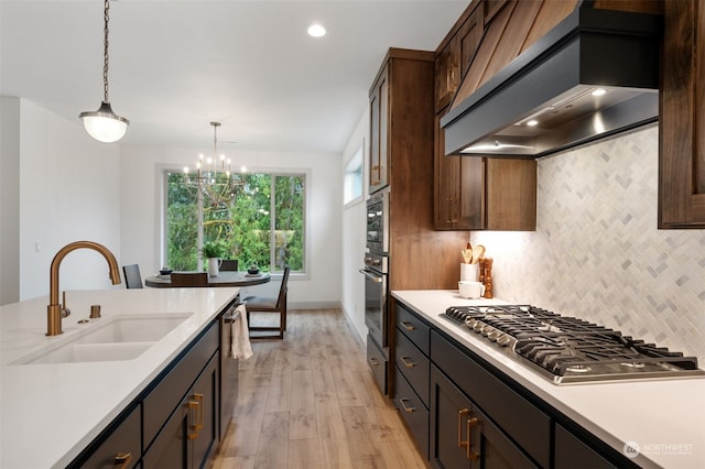 kitchen featuring backsplash, custom range hood, appliances with stainless steel finishes, light hardwood / wood-style floors, and sink