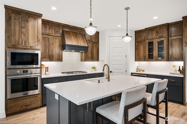 kitchen featuring backsplash, stainless steel appliances, light hardwood / wood-style flooring, and custom range hood