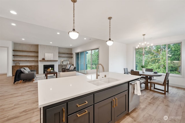 kitchen with sink, light hardwood / wood-style floors, stainless steel dishwasher, and a fireplace