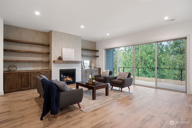 living room with a large fireplace and light hardwood / wood-style flooring