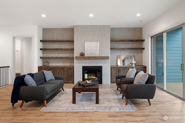 living room featuring light wood-type flooring and a large fireplace