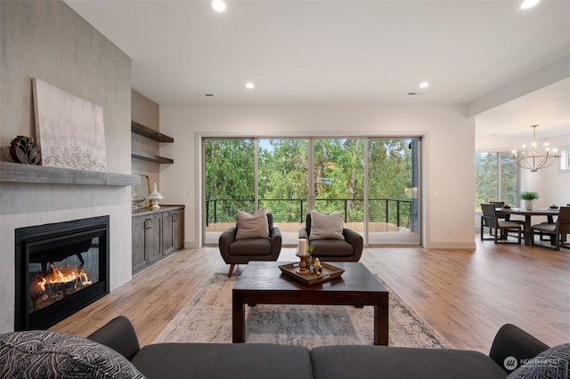 living room with light hardwood / wood-style floors, a large fireplace, and a wealth of natural light