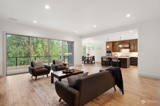 living room with an inviting chandelier, light hardwood / wood-style flooring, and a healthy amount of sunlight