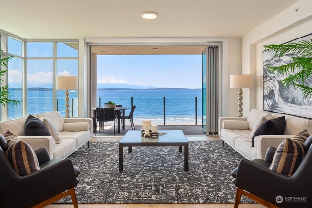 living room featuring hardwood / wood-style flooring, a wall of windows, and a water view