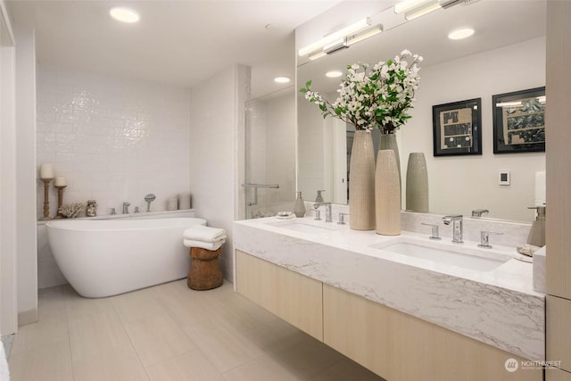 bathroom with recessed lighting, a soaking tub, a sink, and double vanity