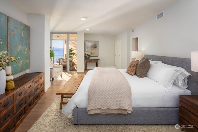 bedroom featuring a water view, wood finished floors, and visible vents