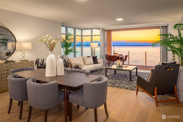 dining room featuring expansive windows, a water view, and light wood-style flooring