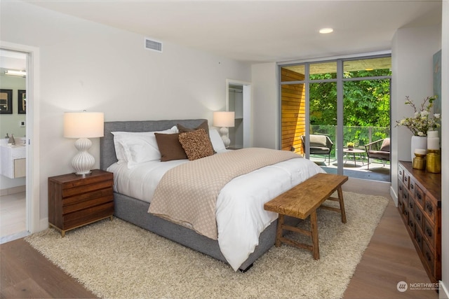 bedroom with access to exterior, expansive windows, visible vents, and wood finished floors