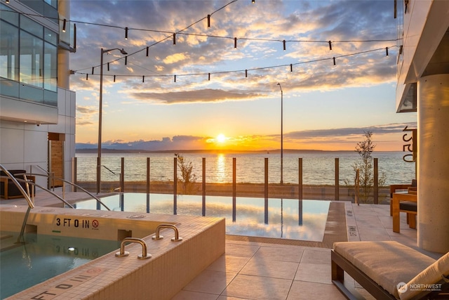 view of pool with a patio area and a water view