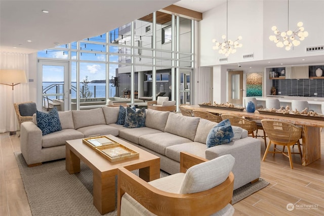 living room featuring a chandelier, a water view, visible vents, and light wood finished floors