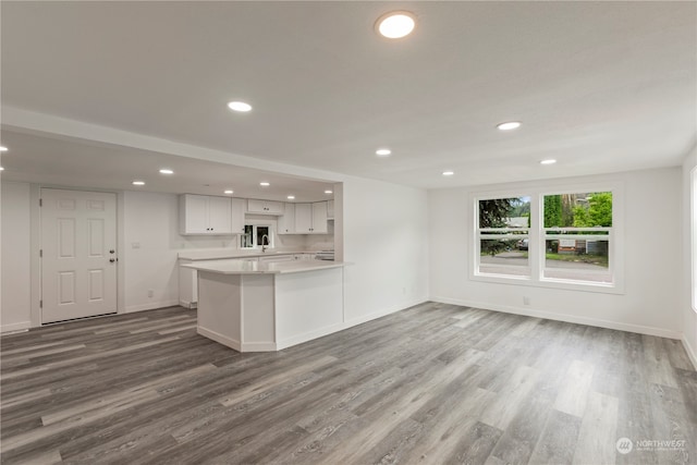 kitchen with wood-type flooring, white cabinets, and kitchen peninsula