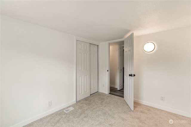 unfurnished bedroom with carpet, a closet, visible vents, and baseboards