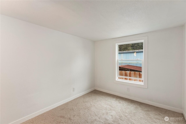 carpeted empty room with a textured ceiling and baseboards