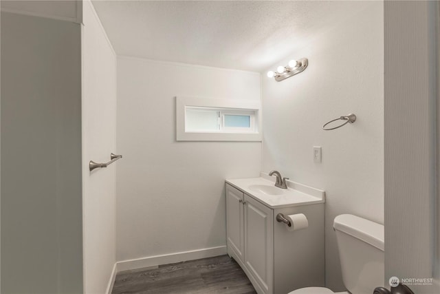 bathroom with a textured ceiling, toilet, wood finished floors, vanity, and baseboards