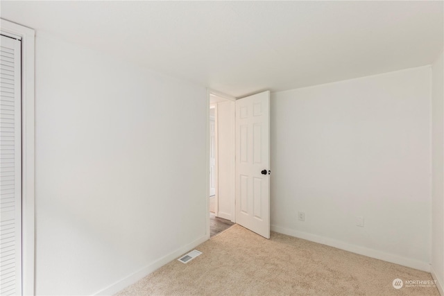 unfurnished bedroom with carpet floors, baseboards, and visible vents