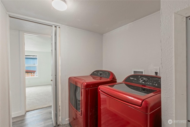 clothes washing area with a textured ceiling, laundry area, wood finished floors, and washing machine and clothes dryer