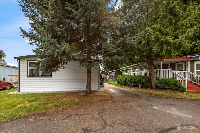 view of side of home with aphalt driveway and a porch