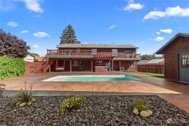 rear view of property with a fenced in pool, a patio, and a balcony