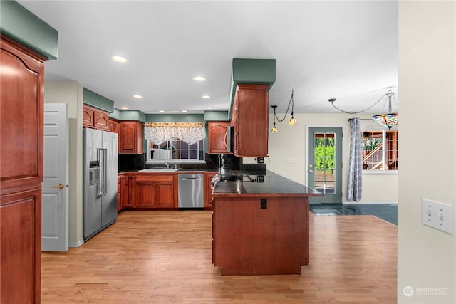 kitchen with backsplash, appliances with stainless steel finishes, kitchen peninsula, sink, and light wood-type flooring