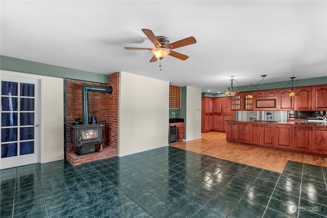 unfurnished living room with a wood stove, dark hardwood / wood-style flooring, brick wall, beverage cooler, and ceiling fan