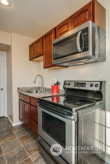 kitchen with sink, appliances with stainless steel finishes, and dark tile patterned flooring