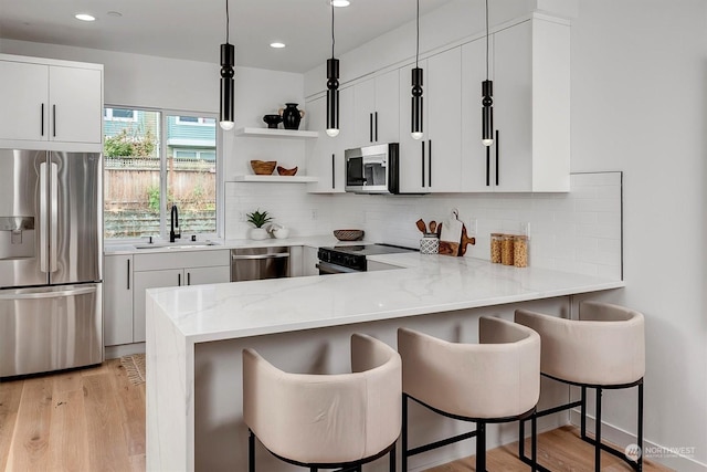 kitchen featuring stainless steel appliances, a sink, a peninsula, and decorative backsplash