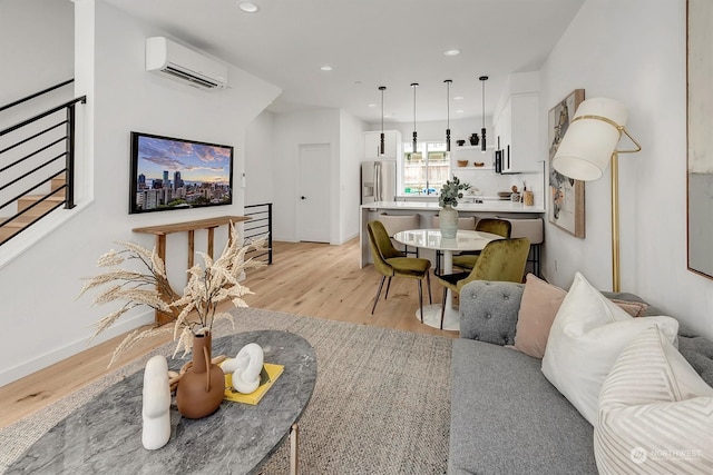 living area featuring baseboards, a wall mounted AC, light wood-style flooring, and recessed lighting