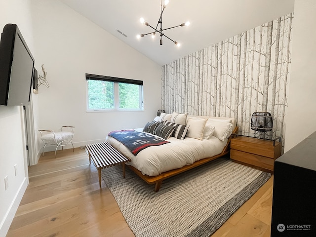 bedroom featuring high vaulted ceiling, light hardwood / wood-style floors, and a chandelier