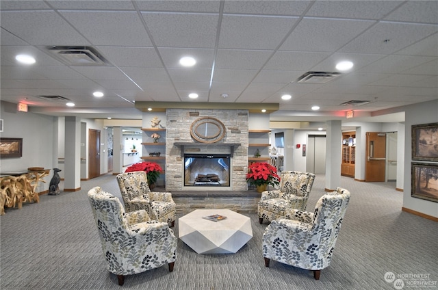 carpeted living room with a fireplace and a drop ceiling