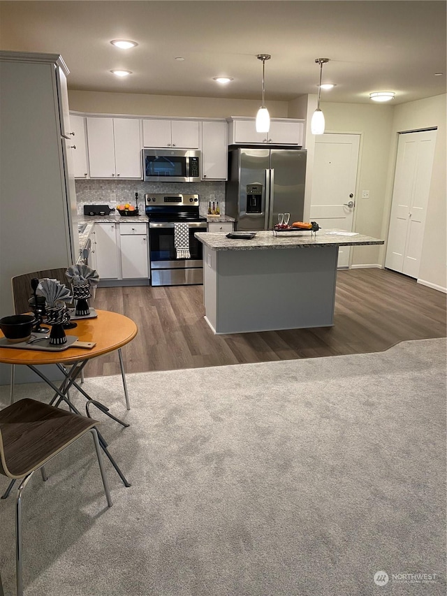 kitchen with hanging light fixtures, decorative backsplash, dark hardwood / wood-style floors, a kitchen island, and stainless steel appliances