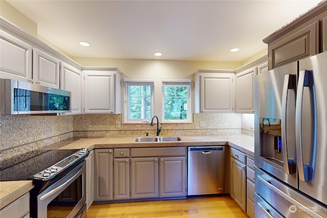 kitchen featuring decorative backsplash, sink, stainless steel appliances, and light hardwood / wood-style flooring