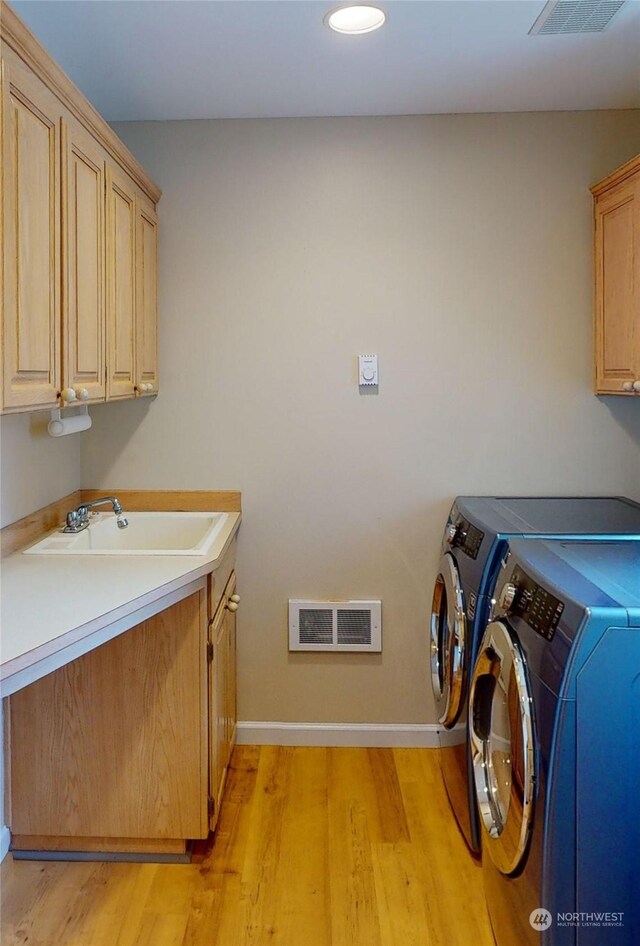 washroom featuring cabinets, light hardwood / wood-style floors, washer and clothes dryer, and sink