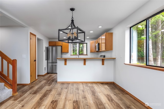 kitchen with a kitchen breakfast bar, stainless steel appliances, kitchen peninsula, and a healthy amount of sunlight